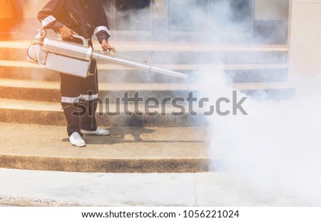health worker of gesture spray or fogging mosquito repellent or fumigates areas as parts of anti dengue fumigation drive to curb breeding site for mosquito cause dengue fever,Zika Virus or Malaria.