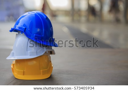 white, yellow and blue hard safety helmet hat for safety project of workman as engineer or worker, on concrete floor