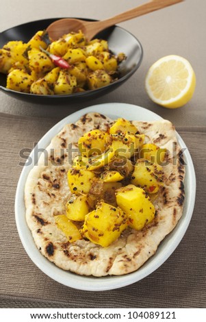 A dish which is an invention of the Western curry houses, Bombay Potato is a hot and spicy accompaniment for curry, or can be eaten as a snack with bread. Here it is shown with naan bread.