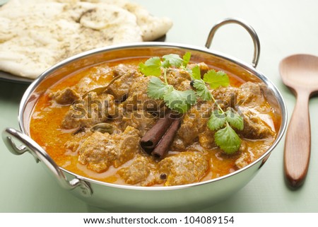 Indian curry lamb rogan josh in a steel karahi, with naan bread.