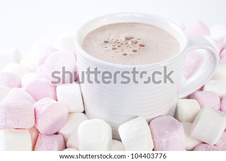 A mug of hot chocolate, surrounded by pink and white marshmallows.