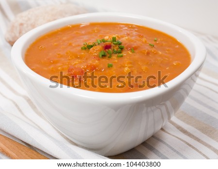 A bowl of lentil and tomato soup garnished with chives.