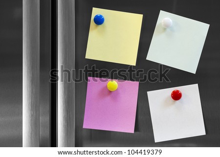 Four colourful notes attached to fridge with fridge magnets, ready for your message.