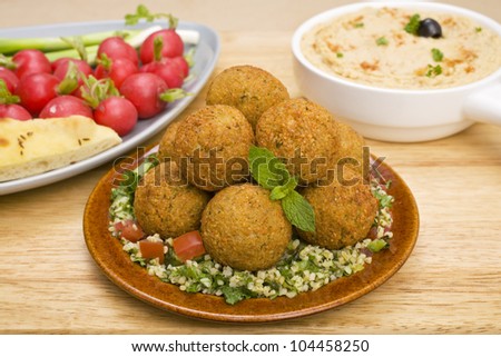 Middle Eastern treats, falafel sitting on a bed of tabbouleh, with hummus and radishes.