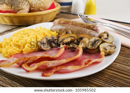 English cooked breakfast with scrambled eggs, sausages, mushrooms and bacon..