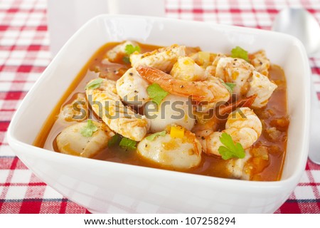 A bowl of delicious Italian fish soup, with prawns, scallops, white fish (gurnard), and a light broth with wine, tomatoes, garlic, carrot and celery.