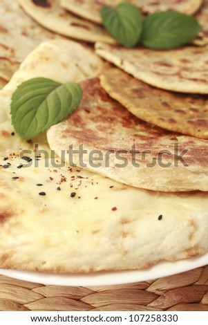 Selection of Indian breads, with naan in the foreground, and various stuffed parathas behind, garnished with mint leaves.