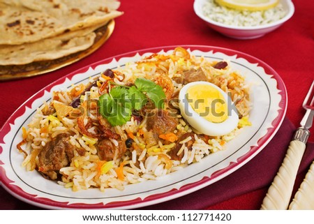 A festive Indian curry, lamb biryani with crisp onion rings, coriander and egg, with chapatis and chutney.