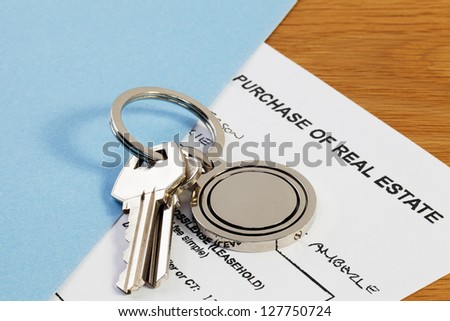 Real estate contract in folder, with keys on key ring.