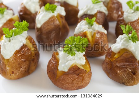 Mini jacket potatoes with a blue cheese and yoghurt dressing and parsley, served up on a platter.