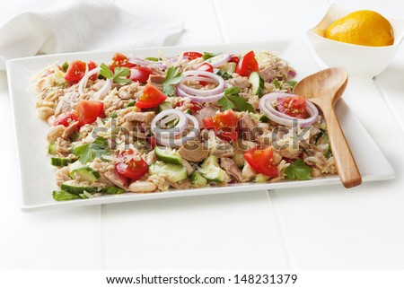 Tuscan bean and tuna salad with tomatoes, cucumber, parmesan and lemon vinaigrette, on a square white platter.