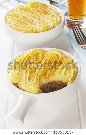 Shepherd\'s Pie - shepherds Pie or Cottage Pie with a glass of lager in a light bright setting.