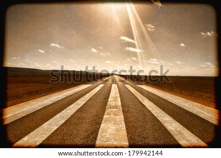 Long straight road with runway markings and sun in picture causing lens flare. Eyre Highway, Nullarbor Plain, Western Australia. Used as emergency runway by flying doctor. Instagram effect.