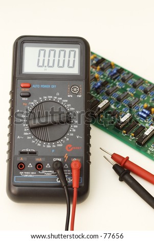 Digital multimeter with test leads and circuit board on pale background
