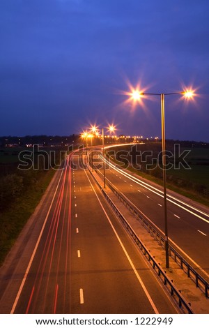 Road at night with traffic trails and street lamps