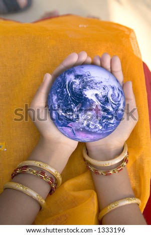 Hands of little Asian Indian girl aged 7, holding planet Earth. Earth from Space courtesy of NASA website.