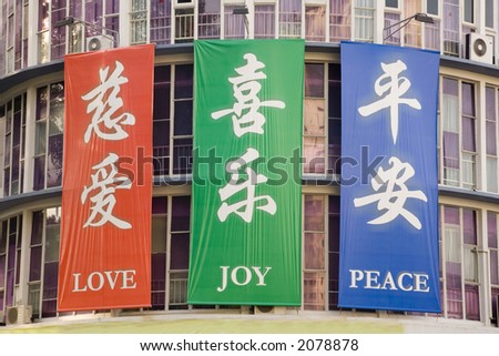 Banners with the words Love Joy Peace in English and Chinese on a church in Singapore, in brilliant red, green and blue.