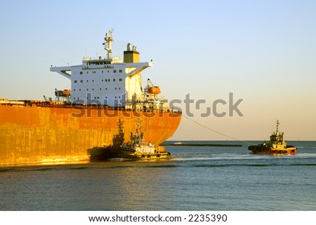 Close up on bridge of bulk ore carrier ship being guided into port by two tugs