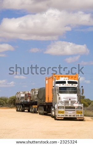 Road Train in rest area, with a load of various types of shipping container and something under a tarpaulin.