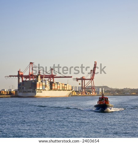 Pilot boat approaching as it goes out to meet ship, container ship in background. Focus on pilot boat.