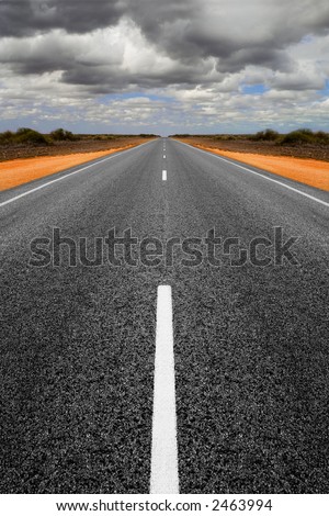 Long straight road in Western Australia with gathering storm clouds overhead. Concepts of trouble ahead and finding a way through. Road is symmetrical has been mirrored.