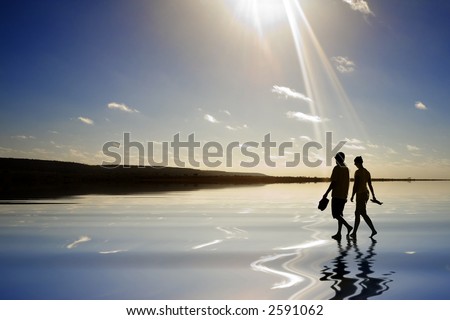 Silhouette of young couple walking through water into ray of light. Sun is just out of shot causing rays. Concepts of walking into the future, or glory, or rapture.