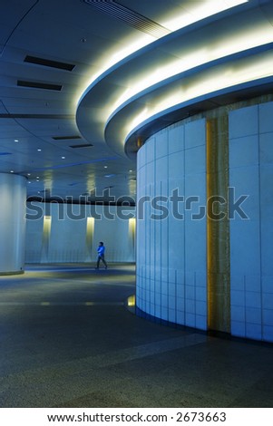 Mall in blue, one person walking in distance is slightly motion blurred.