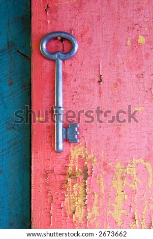 An old key hanging on a nail on an old wooden door. Focus on key, the blue area on the left is slightly less sharp than the pink on the right.