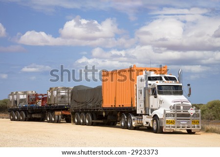 Road train in a rest area, with a load of shipping containers of various kinds, and something covered with a tarpaulin