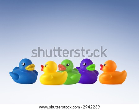 Five rubber ducks in different colours, standing around having a chat with a blue sky background, lots of copy space.