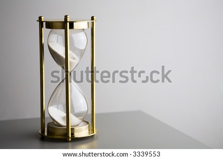 Hourglass or sand timer on soft grey background. Concepts of time passing, running out of time.