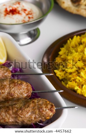 Indian meal of seekh kebab or spicy lamb kebab, yellow rice, naan and yoghourt.