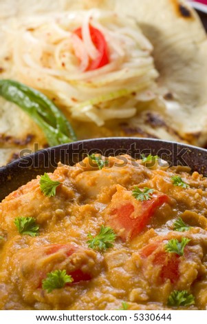 Indian vegetable curry with butter beans, sesame, tomato and spices, with naan bread and onion chutney.