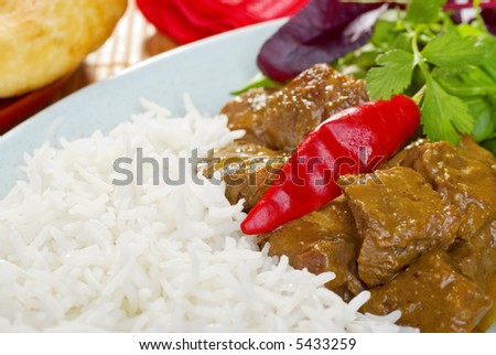 Indian meal of beef curry, with basmati rice, and a garnish of chili and coriander. Korma is enriched with cream and almonds.