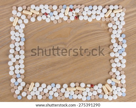 Tablets and capsule arranged into  rectangle frame on a wooden background
