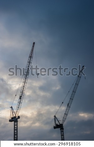 Industrial construction cranes  silhouettes before rain storm.