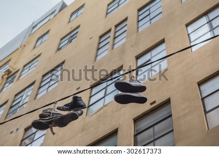 Shoes hanging on power lines in alleyway. Importance of youth projects art recognized.