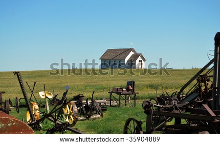 old church sits on a hill with farming machinery in graveyard foreground