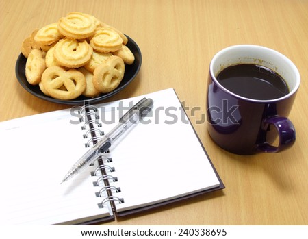 coffee cup with sweet cookie notebook on wood palette