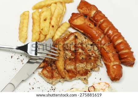 Pork steak with French fries and sausage and vegetables salad on white dish.