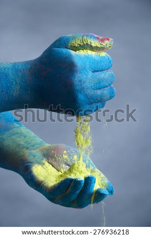 Close-up of blue colored hands holding yellow powder paint