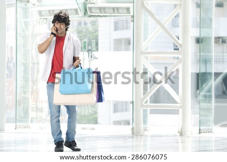 Young man speaking on phone with shopping bags