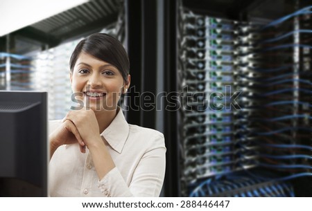 Beautiful young businesswoman smiling while sitting in server room