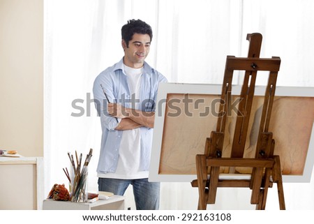 Young handsome man painting at an easel
