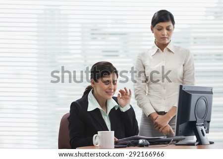 Frustrated businesswoman reading document with female executive