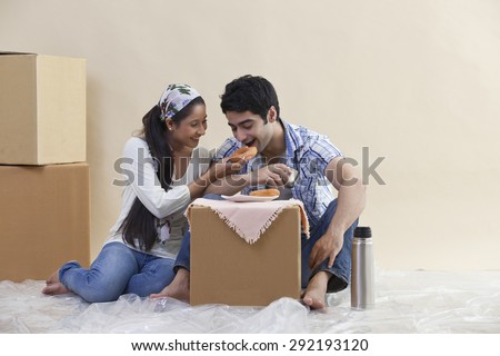 Loving young couple sharing food together at their new home