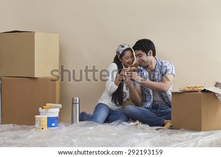 Happy young couple sharing pizza at their new home