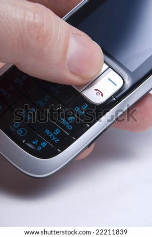 Cell or mobile phone held in hand with thumb operatingit. Shallow focus on action keys.