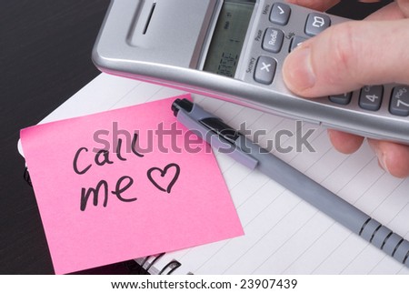 Phone on a spiral notebook with pink note saying CALL ME. Heart Concept for office romance or lifestyle.