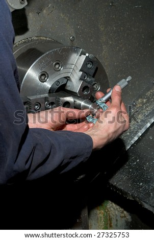 Hands measuring diameter of machined piece using a tool on a CNC lathe